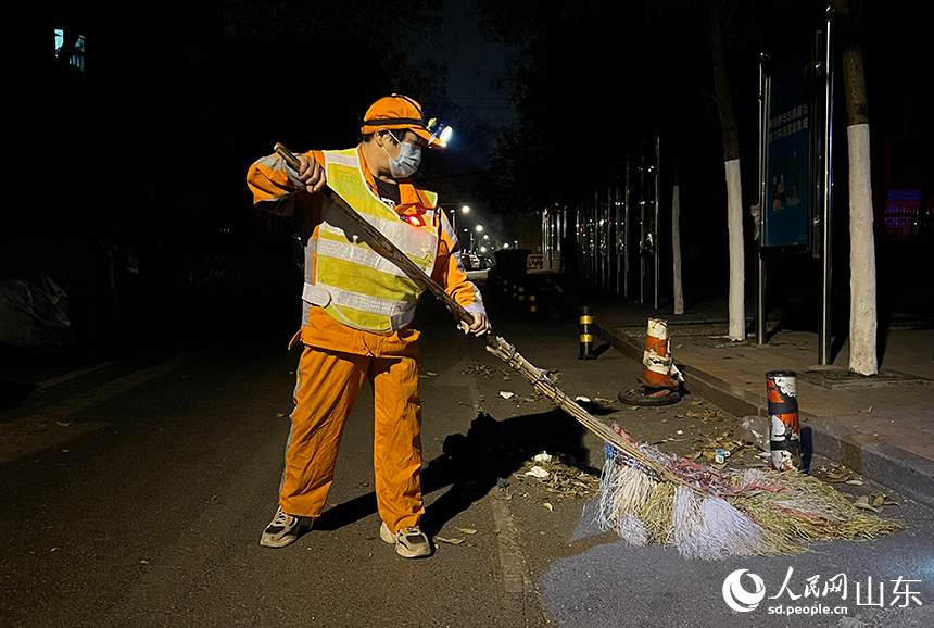 王海菊借著路燈光開始清掃道路。人民網 劉祺攝
