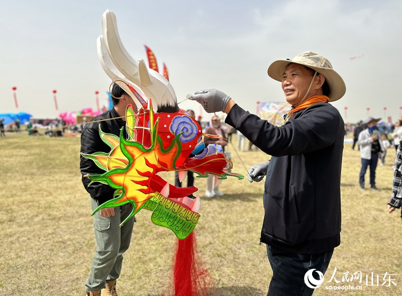 風箏比賽參賽者正在整理龍頭蜈蚣風箏，為放飛做準備。人民網 喬姝攝