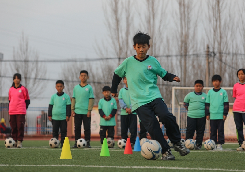 12月5日，學生們在鐵營鎮閆集小學足球場進行帶球訓練。