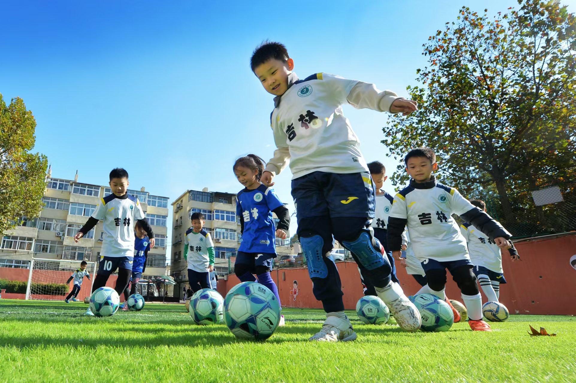 2024年11月18日，在山東青島吉林路小學(xué)開展的足球冬訓(xùn)活動(dòng)上，孩子們?cè)诰G茵場上進(jìn)行帶球訓(xùn)練。