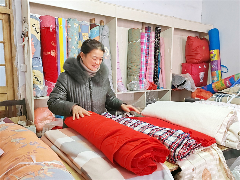 圖為王素蕓在整理店內銷售的布匹