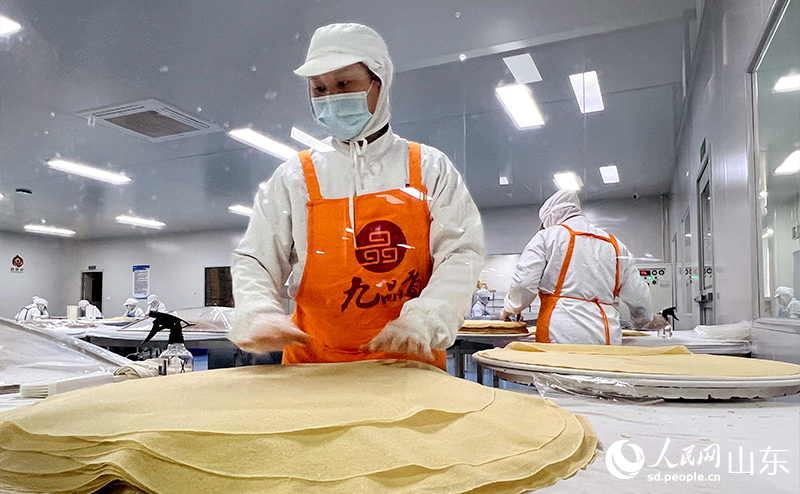 工人們手法嫻熟地將新鮮出鏊的煎餅層層疊起。人民網(wǎng)記者 劉祺攝