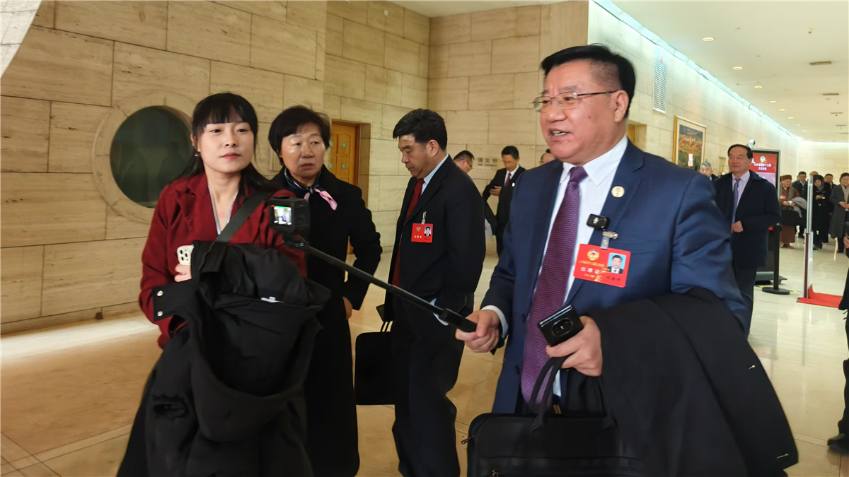 1月19日，山東省政協(xié)十三屆三次會議開幕，一位委員走出會場，邊走邊接受采訪。人民網(wǎng)記者宋翠攝
