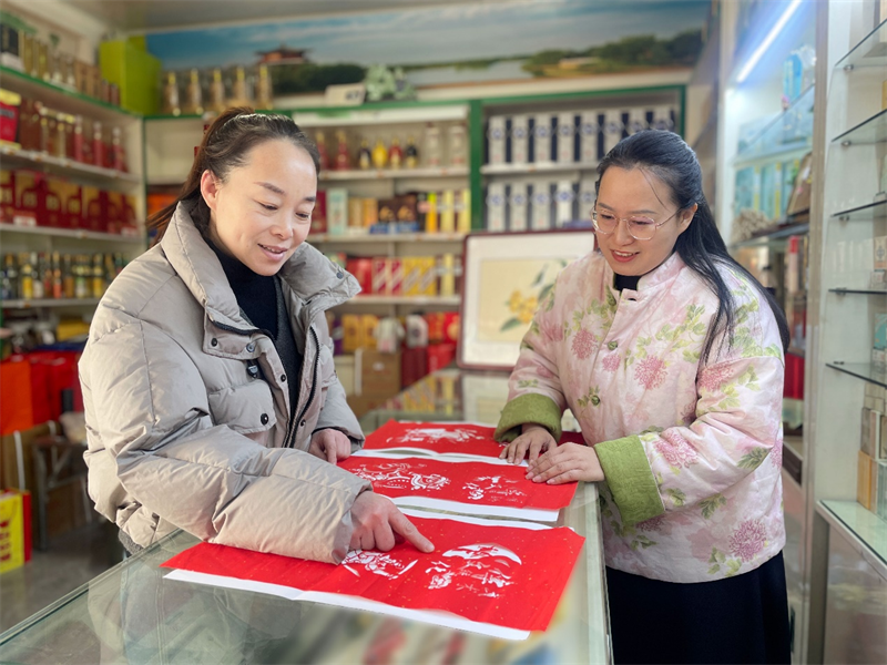 圖為顧客饒有興趣地觀看沈文瑩（右）的剪紙作品