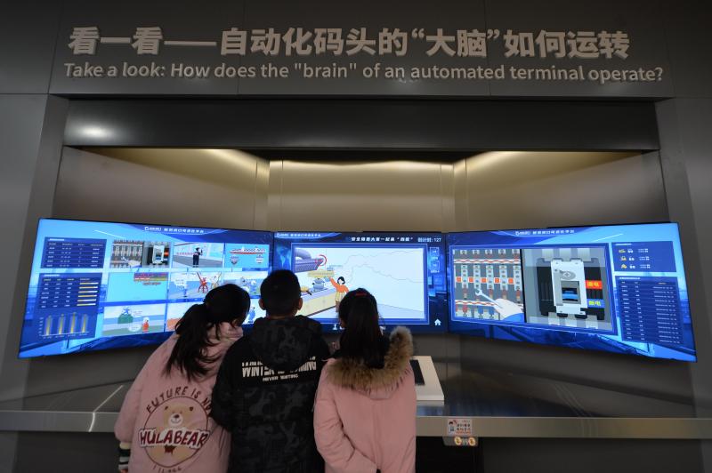 三名學生在體驗自動化碼頭“大腦”平臺。