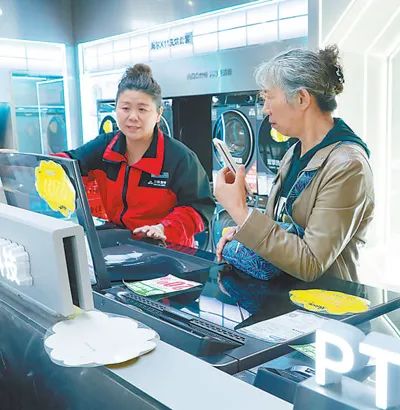 圖為顧客（右）在濟南市歷城區三聯家電洪家樓店挑選洗衣機并咨詢國補政策。劉 霖攝