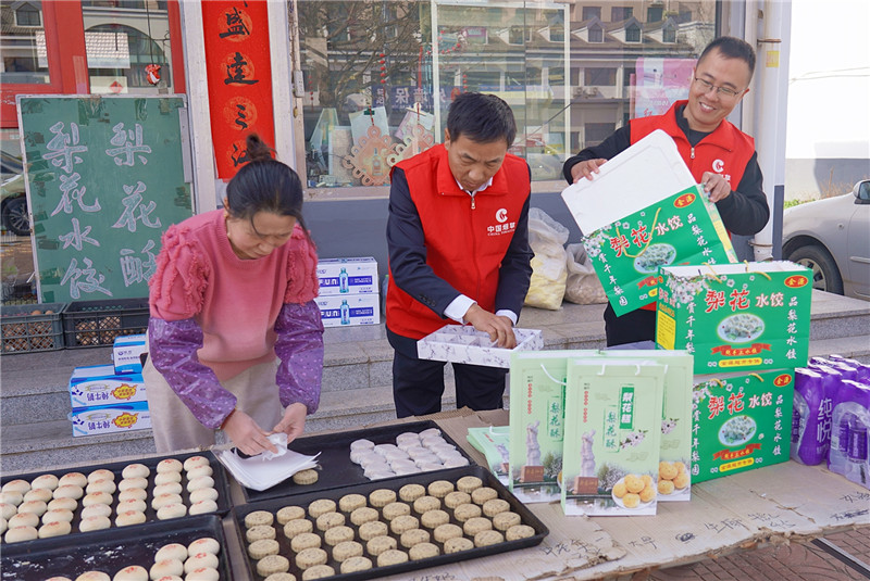 圖為志愿者幫助張蘭英（左一）打包梨花系列產品