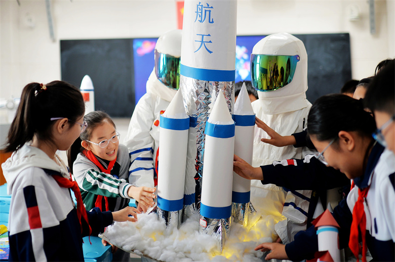 2025年4月24日，在山東省青島市市北區洛陽路第二小學開展的“中國航天日”科普活動上，學生們在擺放自制的運載火箭模型。