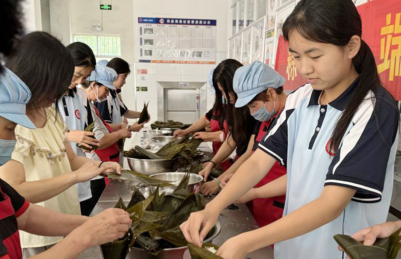 師生們圍在一起，體驗包粽子的樂趣。鄧璇攝