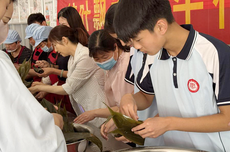 師生們圍在一起，體驗包粽子的樂趣。鄧璇攝