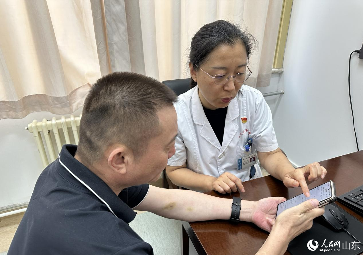 醫生徐冬玲為患者陳濤分析手機APP中的血壓變動曲線。 人民網 喬姝攝